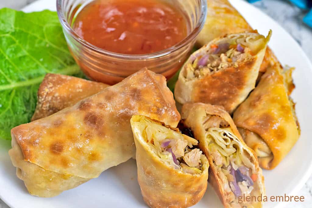 Egg Rolls on a white platter with sweet chili dipping sauce.