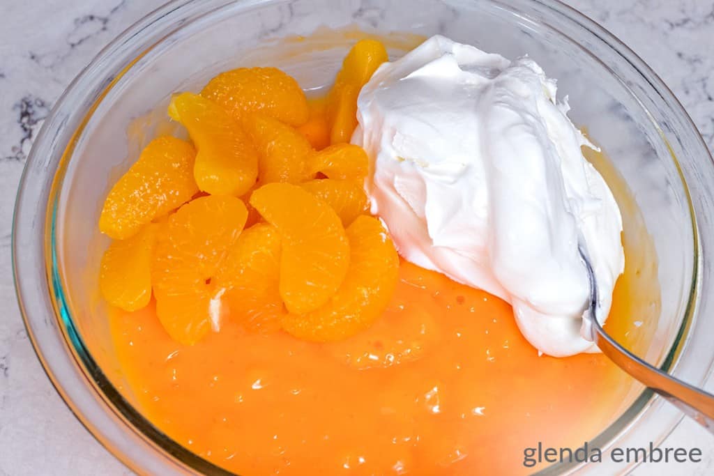 Mandarin orange segments and Cool Whip ready to be mixed into thickened orange salad mixture.