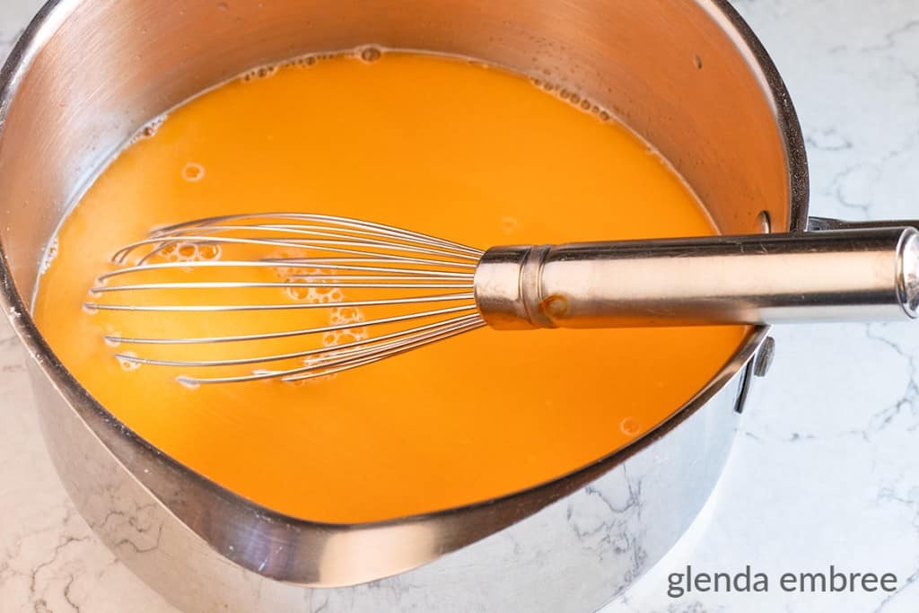 Sauce pan with orange gelation, vanilla pudding mix and tapioca pudding mix whisked together in preparation for cooking