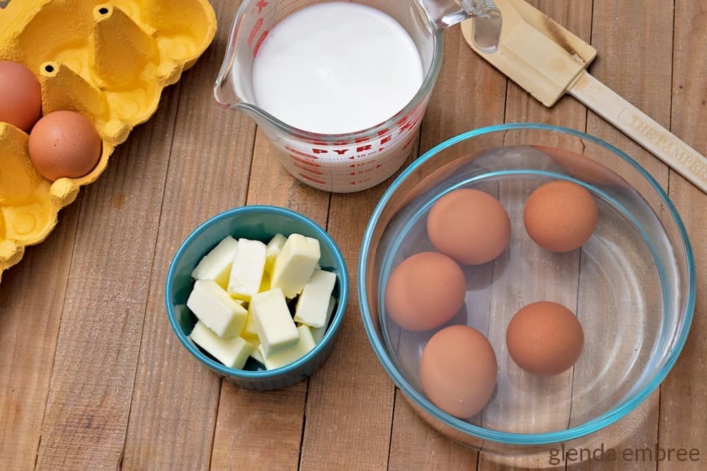 Butter, eggs, milk and a spatula on a wooden tabletop