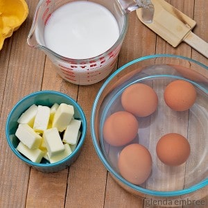 Butter, eggs, milk and a spatula on a wooden tabletop