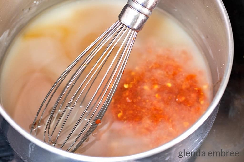 Adding chili sauce, sugar, vinegar and soy sauce to a pan