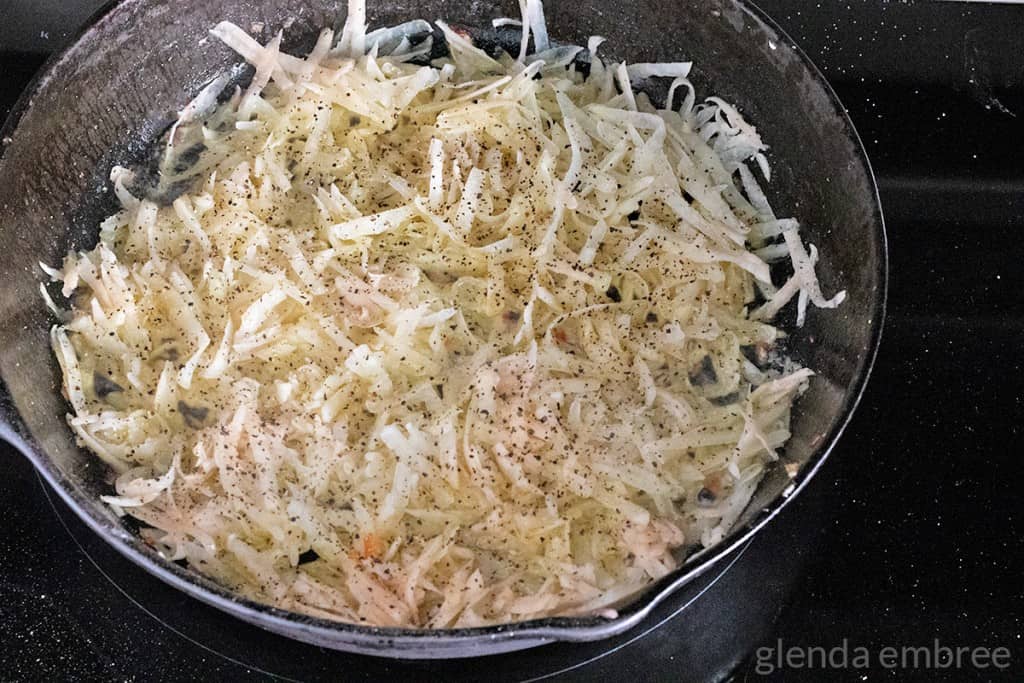 grated potatoes in cast iron skillet
