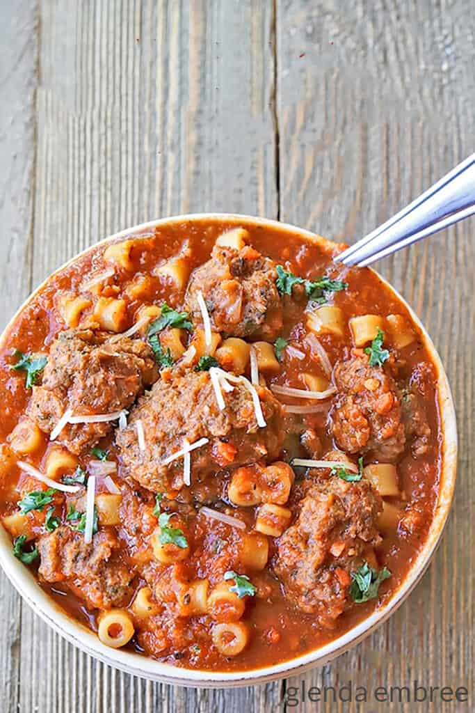 Meatball Stew in an ivory stonware bowl.  There's a spoon in the bowl and it's all sitting on a barn board table.