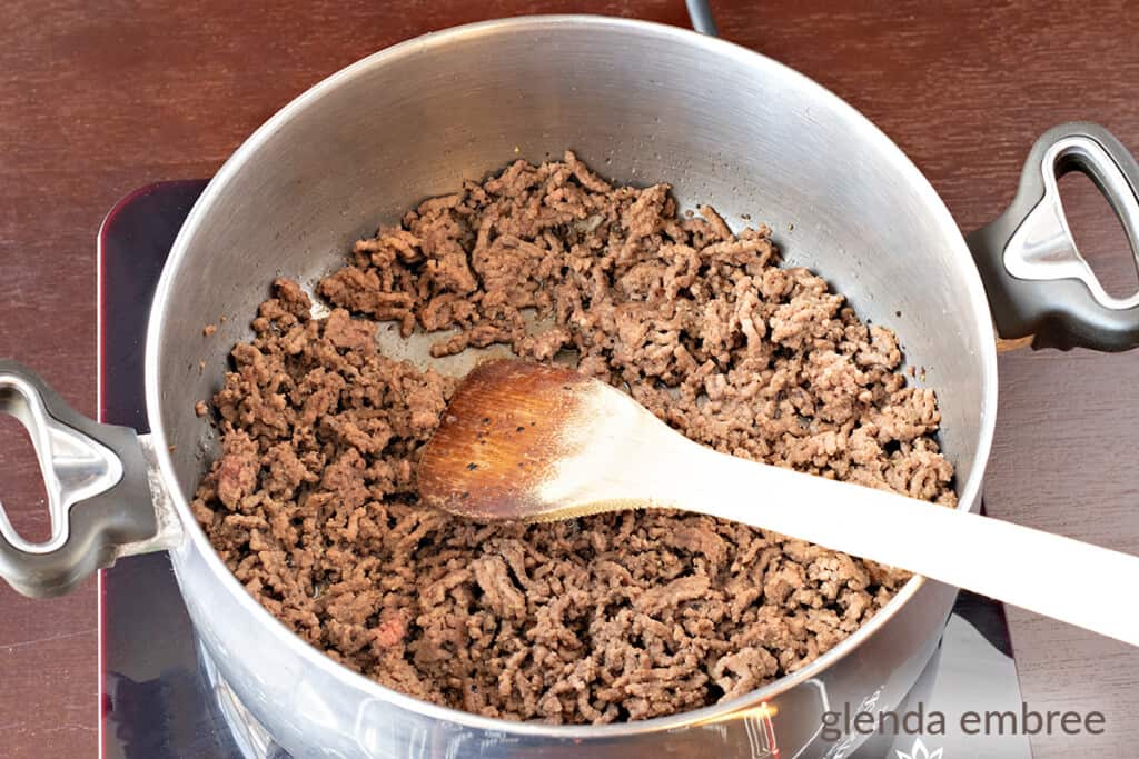 ground beef, browned in a pot with a wooden spoon