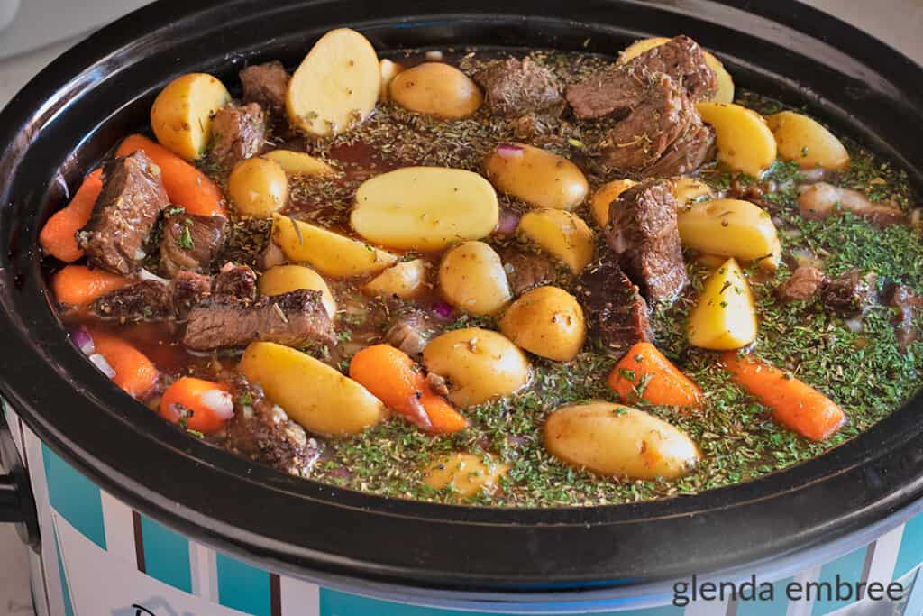 slow cooker with all ingredients for beef stew added and ready to be cooked