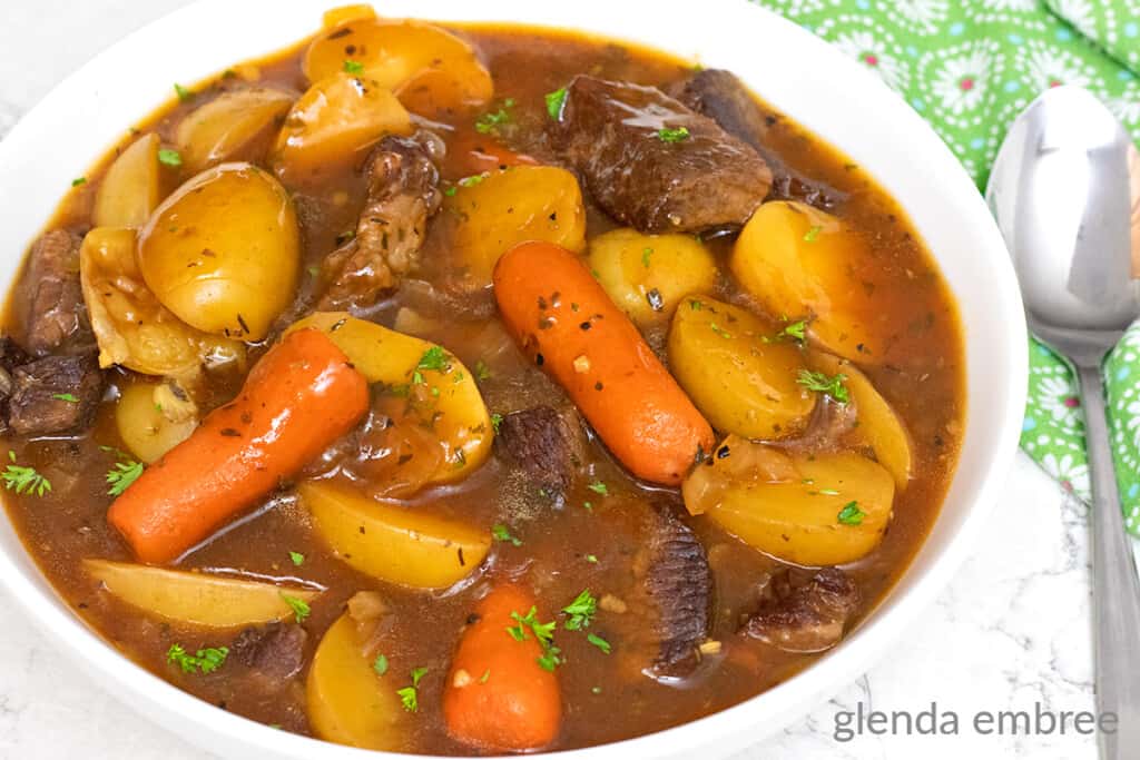 Slow Cooker Beef Stew served in a white bowl next to a green print napkin