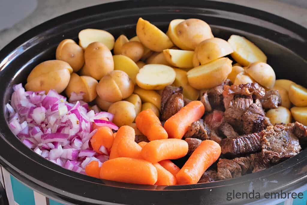 potatoes, beef, carrots and onions in a slow cooker
