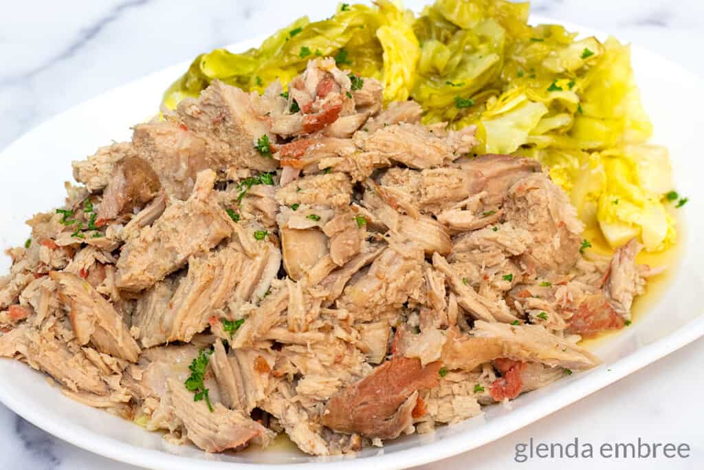 Kalua Pork on a white platter with steamed cabbage.
