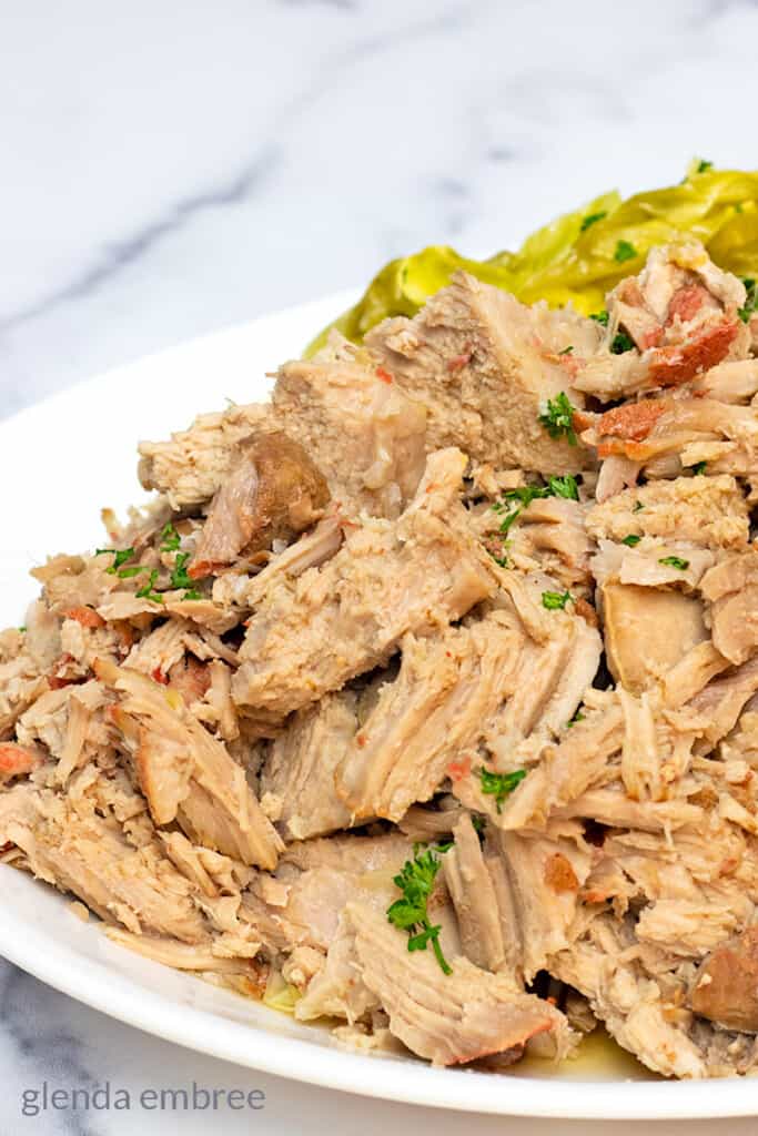 Slow Cooker Kalua Pork on a white platter with steamed cabbage.  Easy slow cooker pork loin recipe.