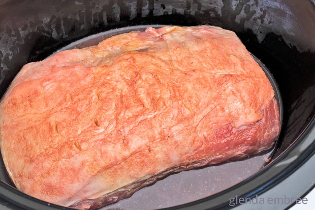raw seasoned pork loin in a slow cooker