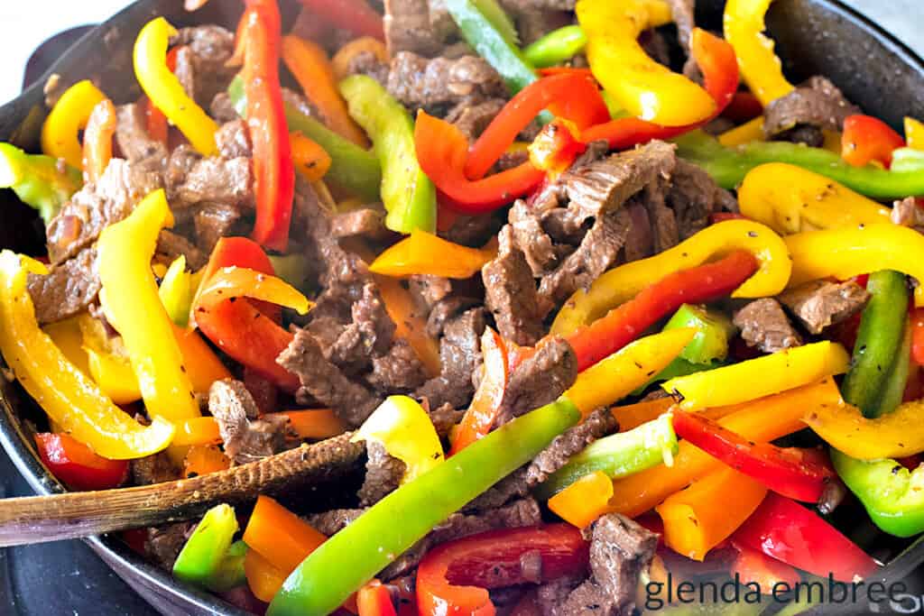 bell peppers added to skillet with steak strips