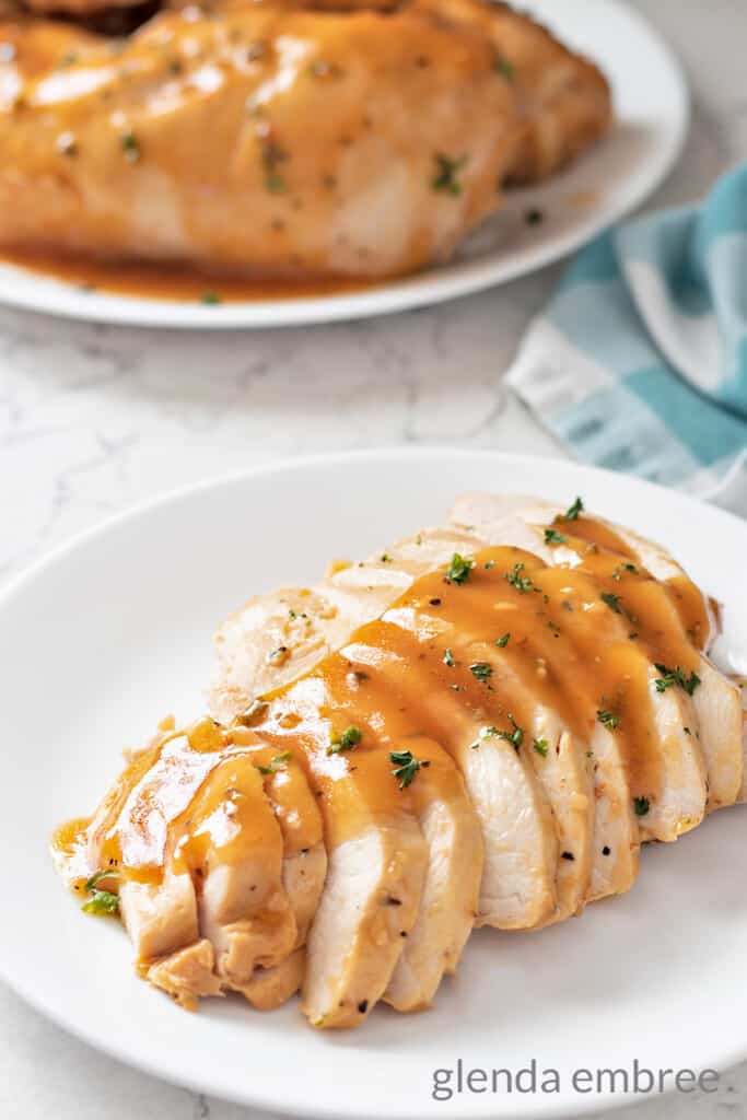 Slow Cooker Pineapple Chicken sliced on a plate and drizzeled with pineapple pan sauce