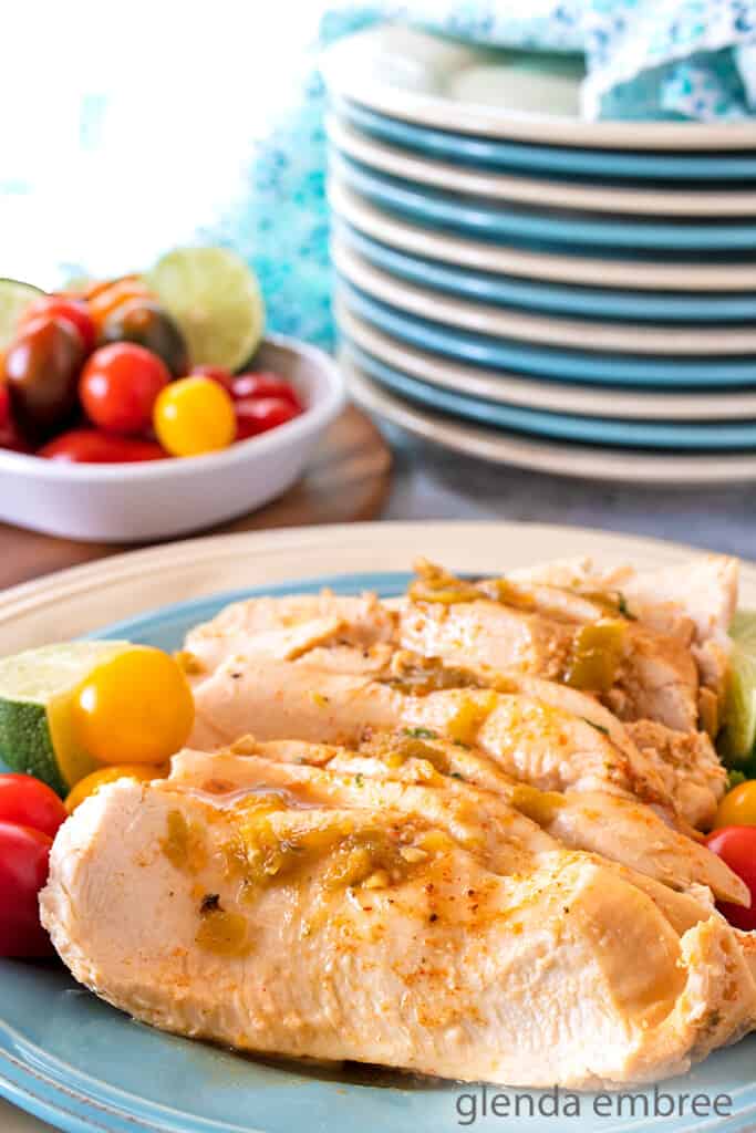 slow cooker southwest chicken sliced on a plate with tomatoes and quartered limes