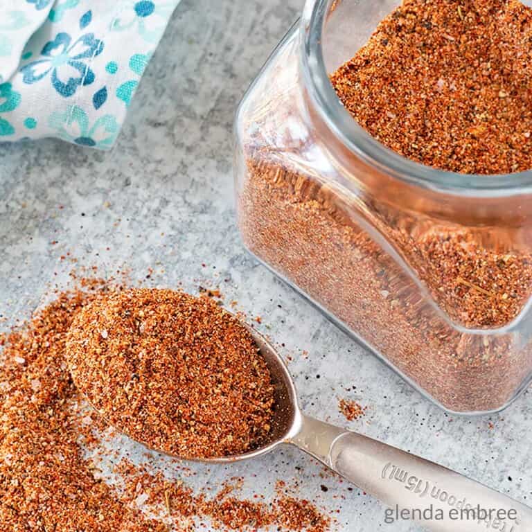 Southwest Seasoning Blend in a jar and spilling out of a measuring spoon on a concrete counter top