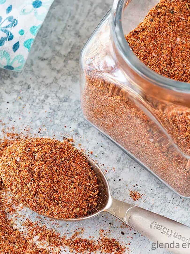 Southwest Seasoning Blend in a jar and spilling out of a measuring spoon on a concrete counter top