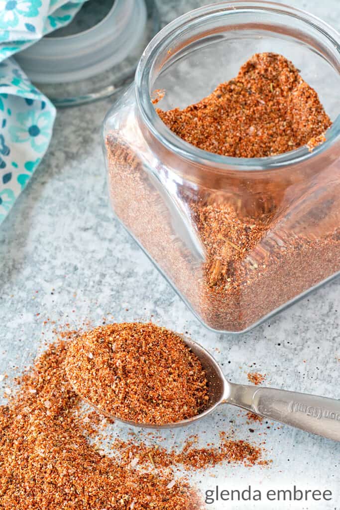 Southwest Seasoning Blend in a jar and spilling out of a measuring spoon on a concrete counter top