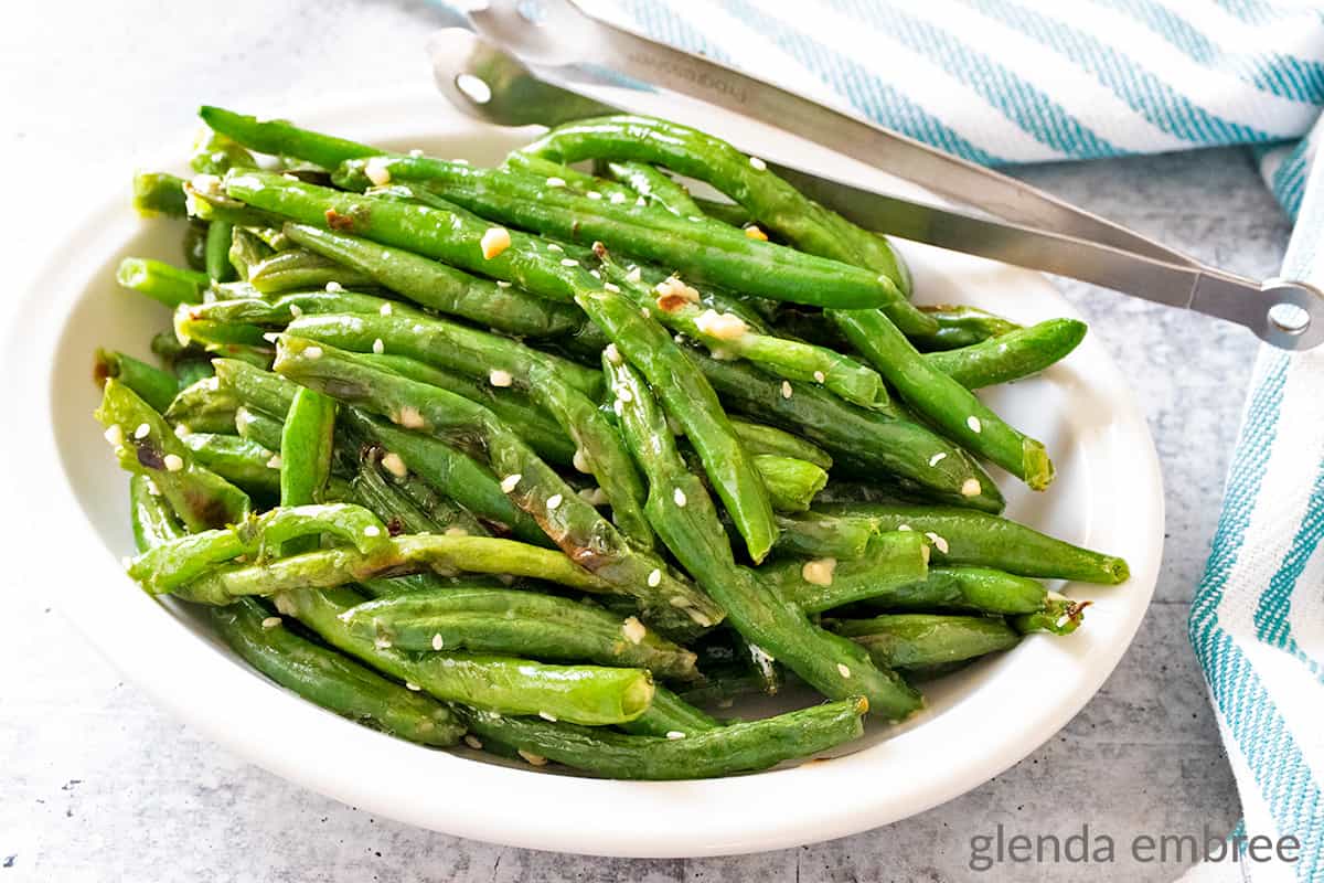 Air Fryer Green Beans with Garlic Butter Sauce in a white oval serving bowl.