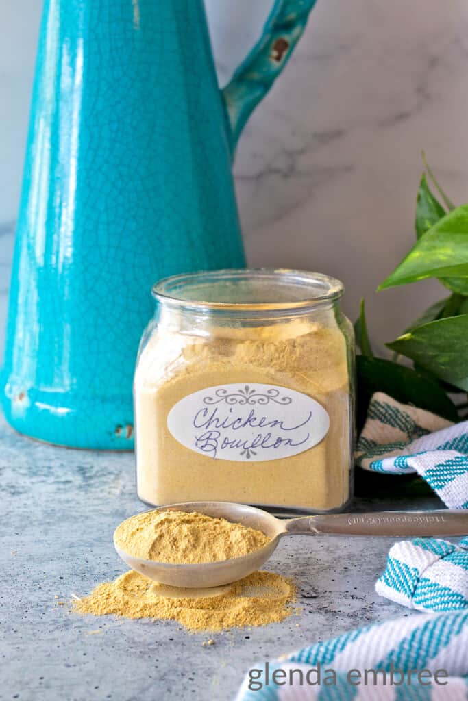 Chicken Bouillon Powder in an apothecary jar and spilling out of a Tablespoon onto the counter