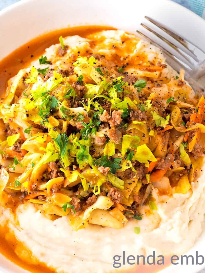 Ground Beef and Cabbage over Mashed Potatoes in a white stoneware bowl sitting on a concrete counter