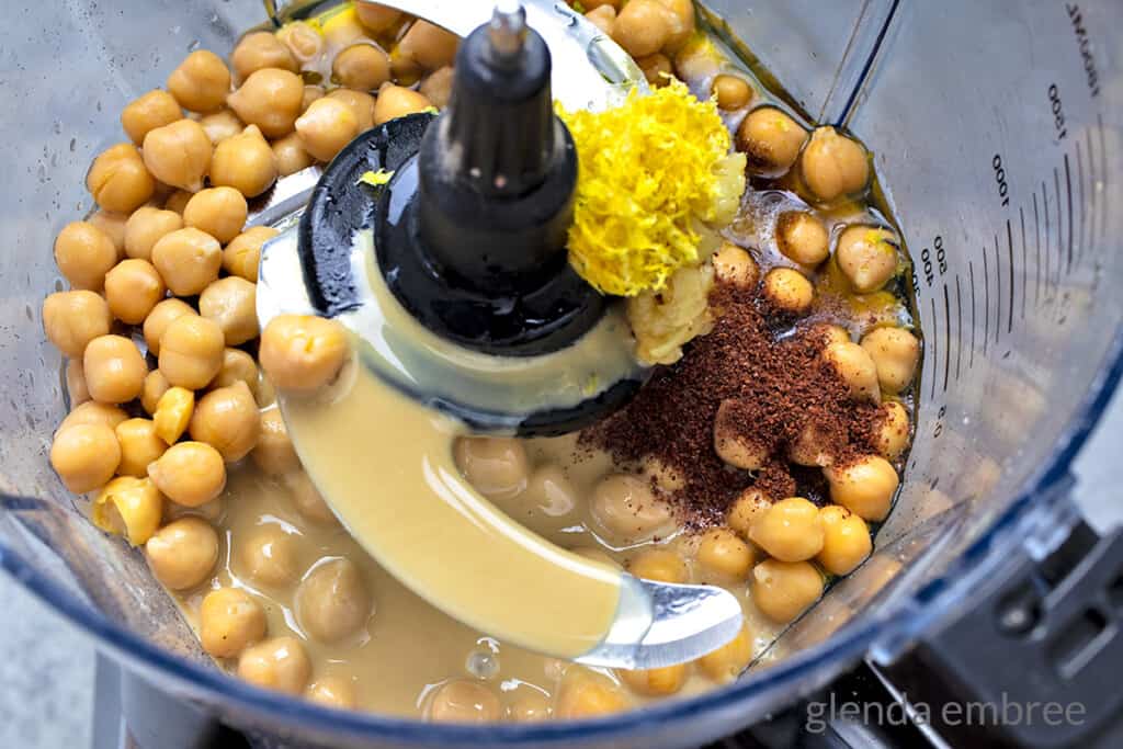 chickpeas, cumin, sumac, lemon zest, lemon juice, olive oil, tahini in bowl of food processor