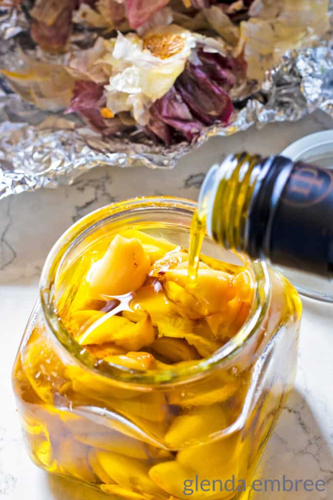 roasted garlic cloves covered in olive oil in an apothecary jar