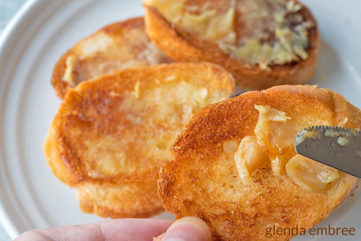garlic toast rounds made by spreading roasted garlic on toasted bread