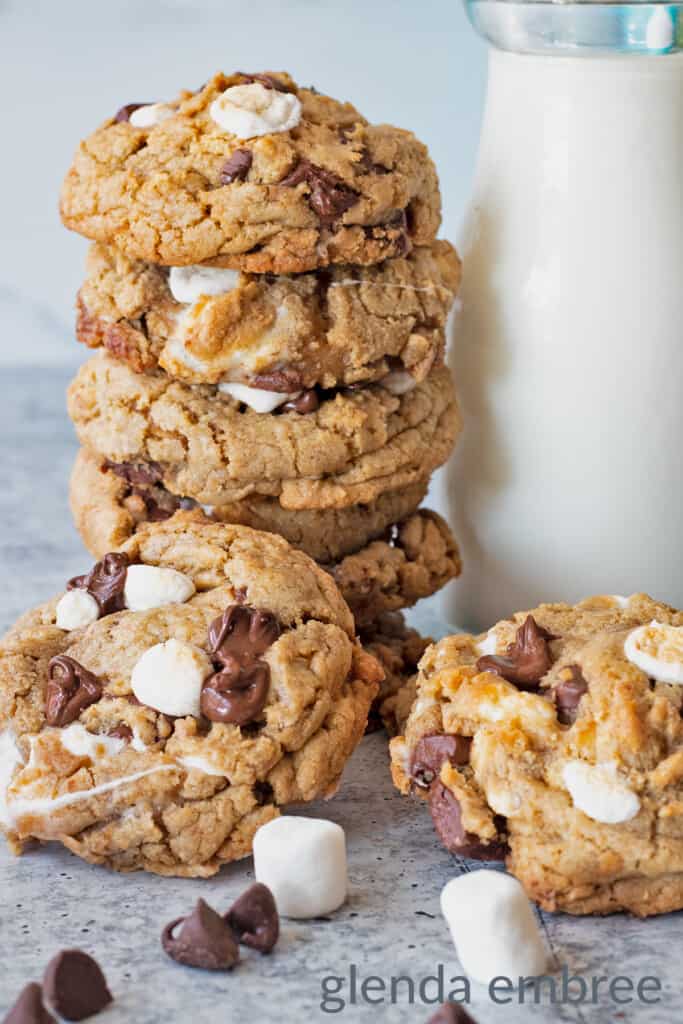 s'mores cookies stacked against a bottle of milk with 2 cookies propped in front