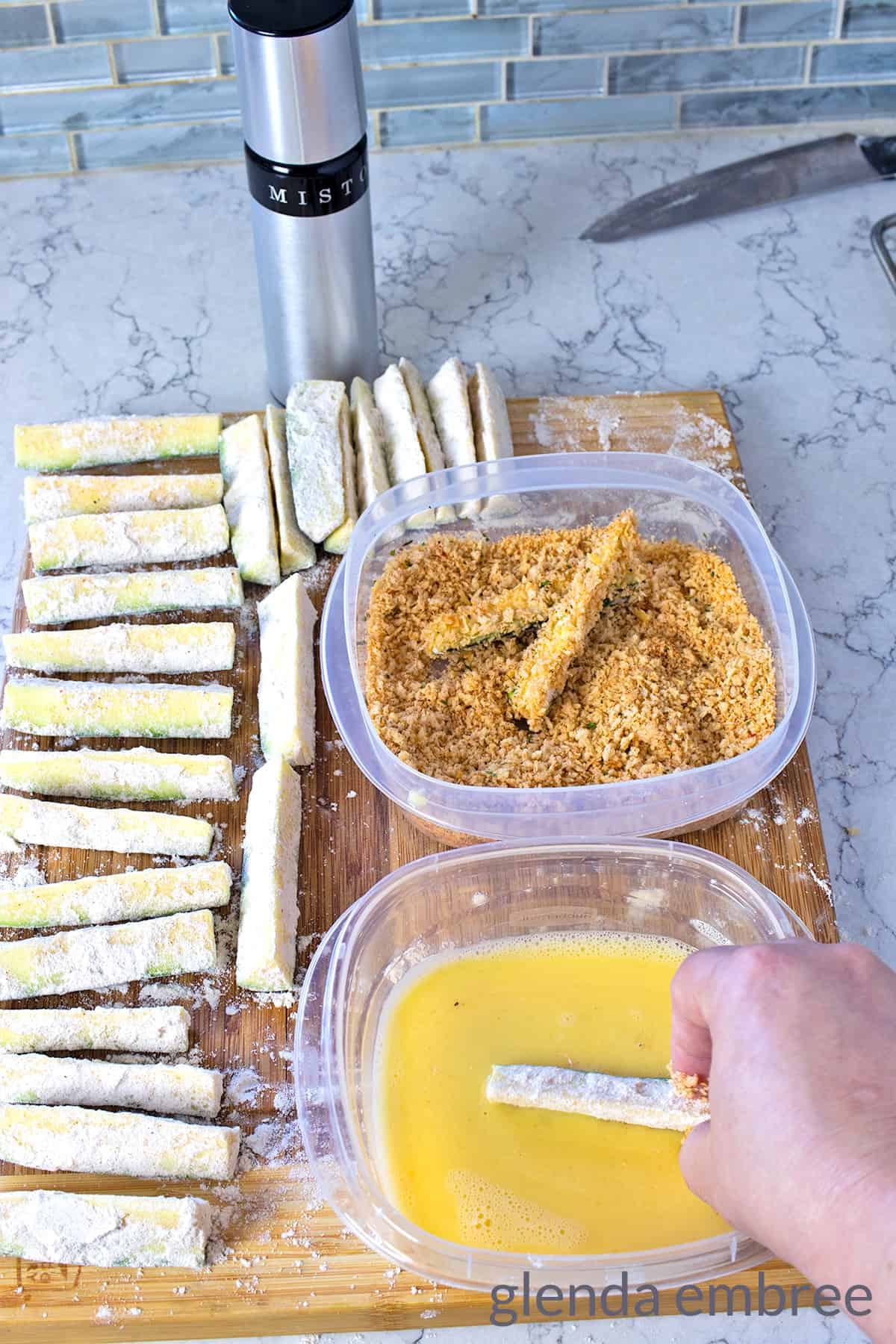 dipping flour dredged zucchini wedges into egg and then panko bread crumbs for air frying