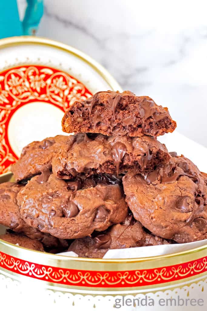 double fudge chocolate malt cookies with black walnuts in an antique tin with black walnuts and chocolate chips strewn about the counter