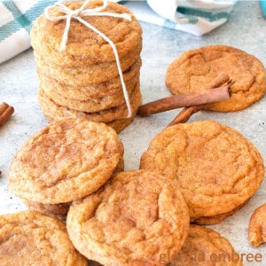 chai spiced pumpkin snickerdoodles on a concrete counter with cinnamon sticks and one stack of cookies tied with a piece of white twine