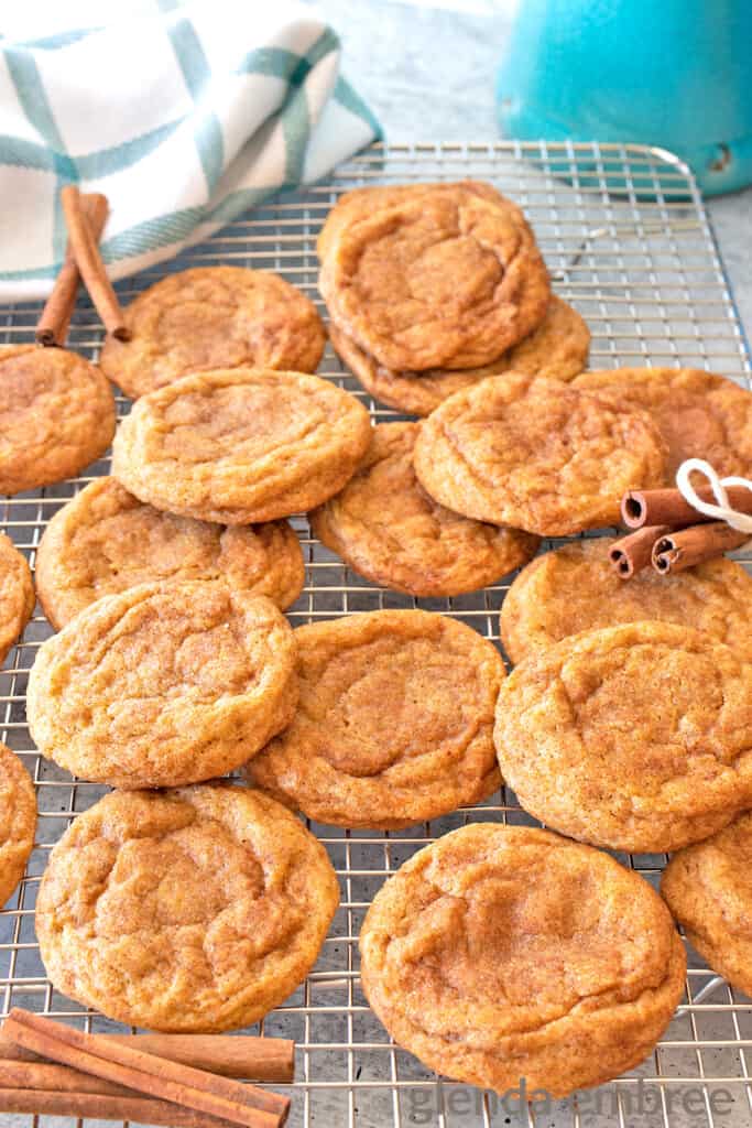 chai spiced pumpkin snickerdoodles on a cooling rack with cinnamon sticks