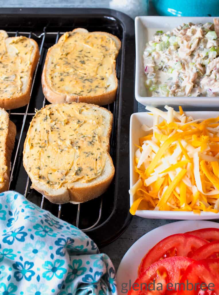 Ingredients for a Tuna Melt Open Face Sandwich: Texas Toast spread with garlic herb butter, creamy tuna salad, grated cheddar and monterey jack cheeses and a garden tomato, thinly sliced.