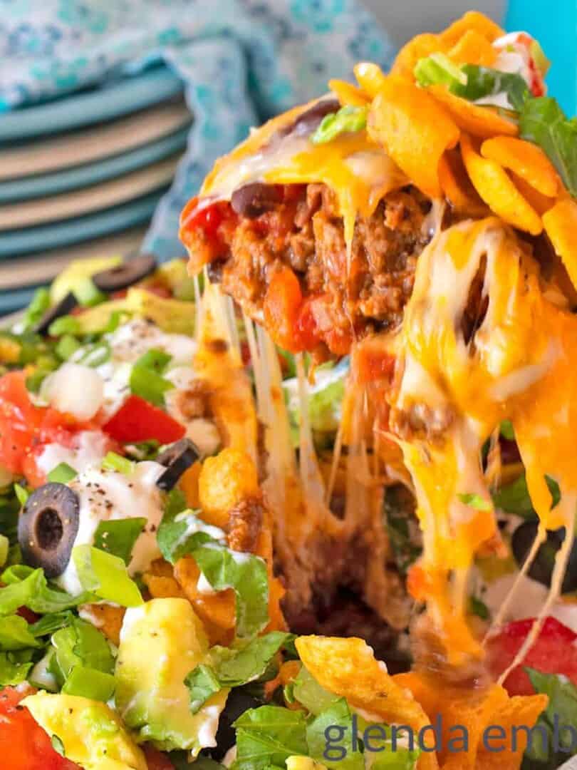 Walking Taco Casserole being served and the cheese is stretching from the casserole dish to the serving spoon