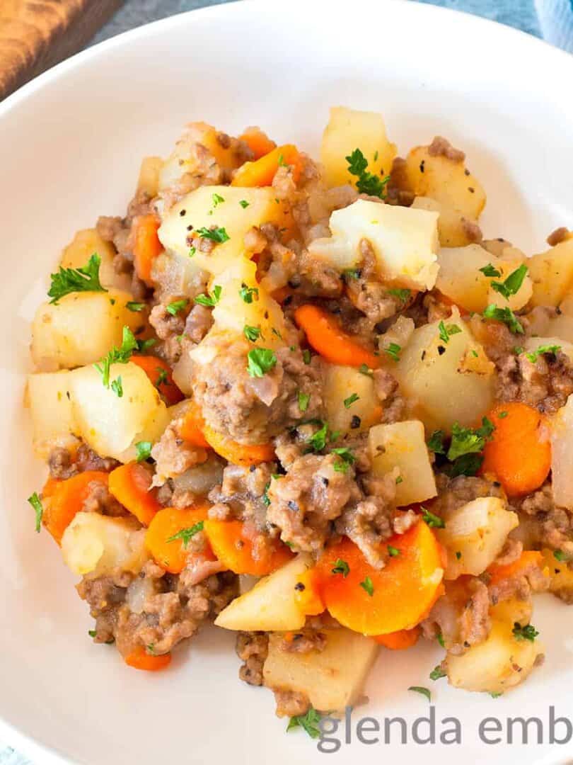 Ground Beef and Potatoes Casserole in a shallow white bowl on a concrete counter