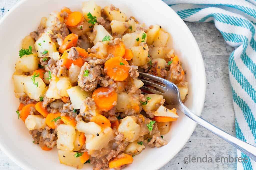 Ground Beef and Potatoes Casserole in a shallow white bowl on a concrete counter