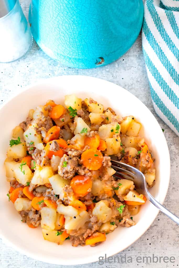 Ground Beef and Potatoes Casserole in a shallow white bowl on a concrete counter.   Easy Potato and Ground beef recipe  for 30 minute meal prep.