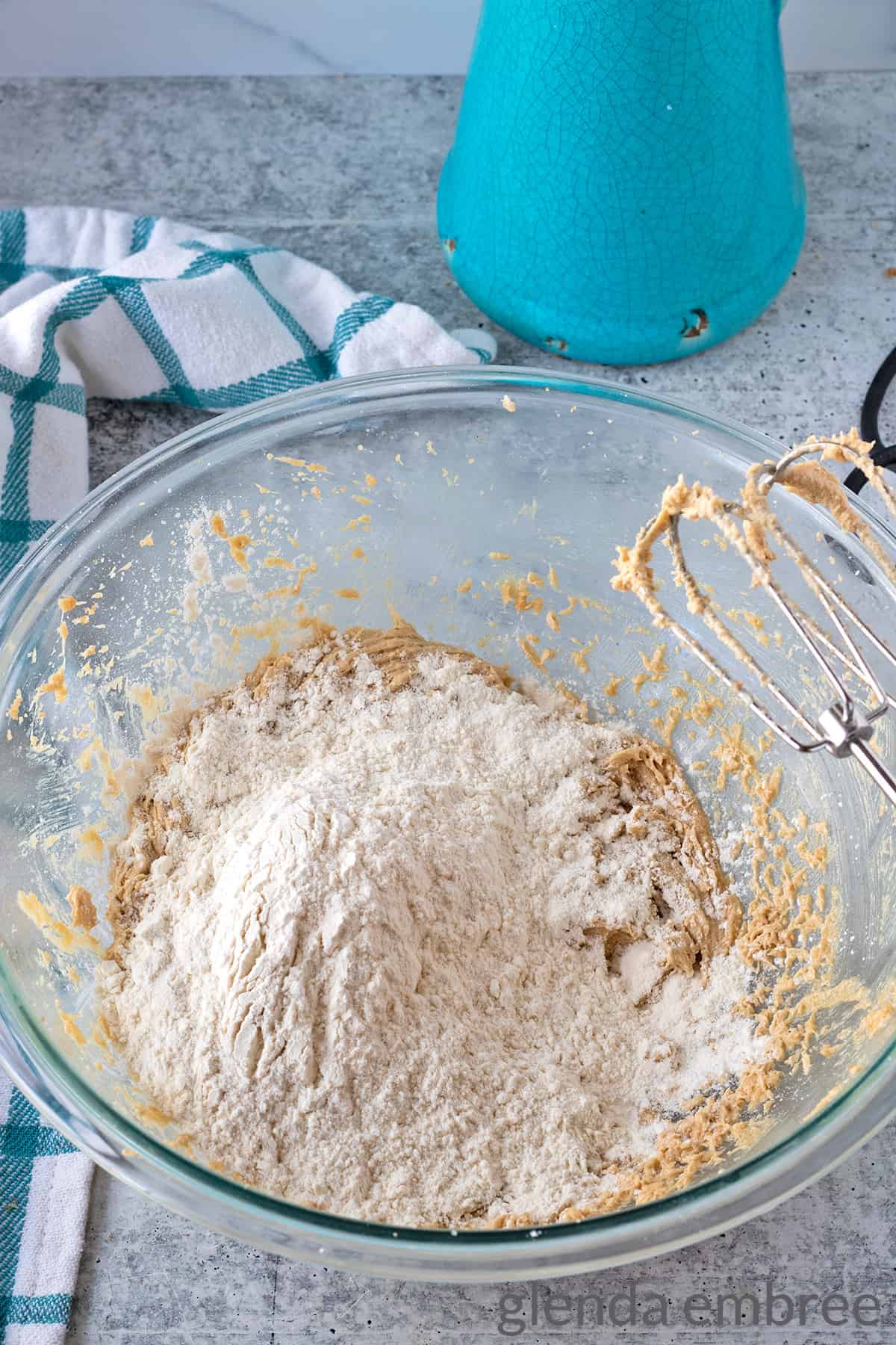 dry ingredients added to batter in a clear bowl on a concrete countertop