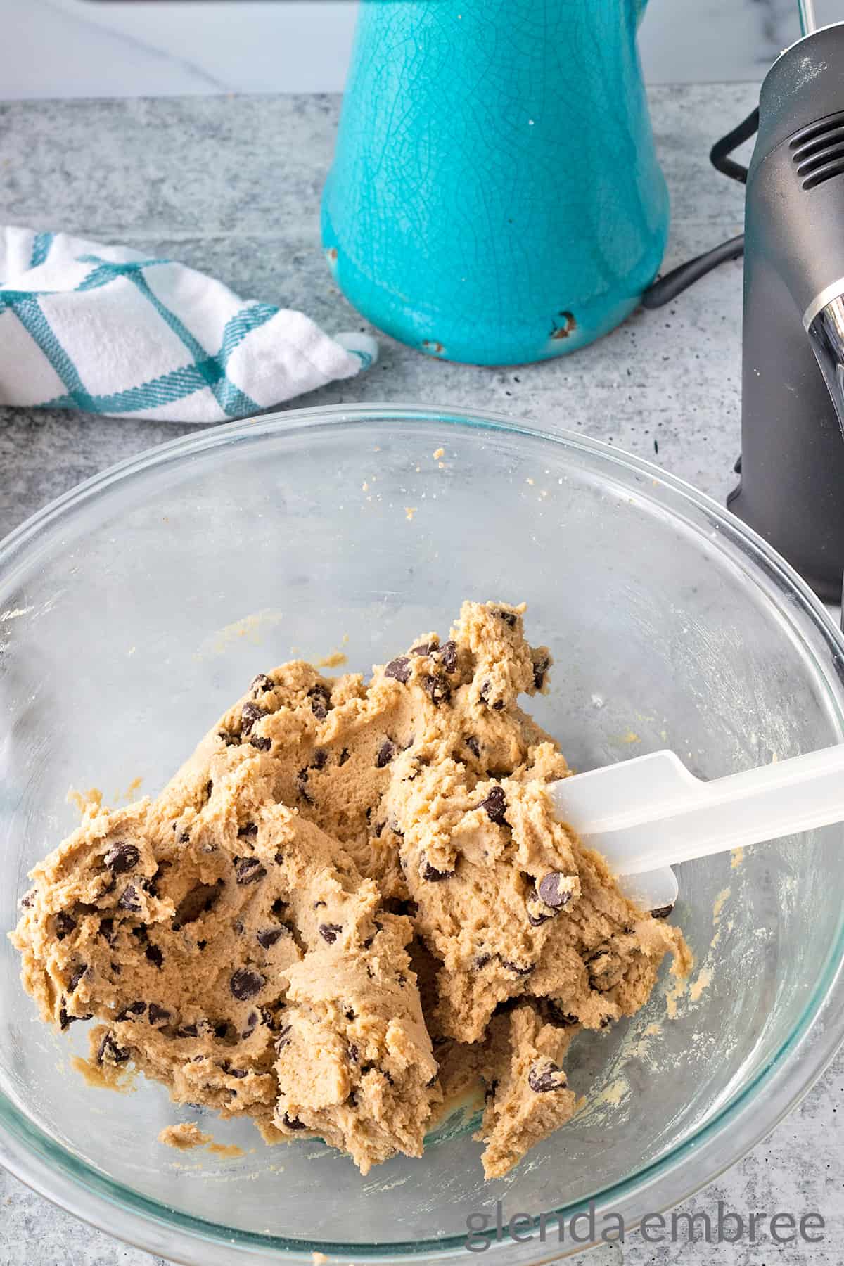 chocolate chip cookie dough completed in a clear bowl on a concrete countertop