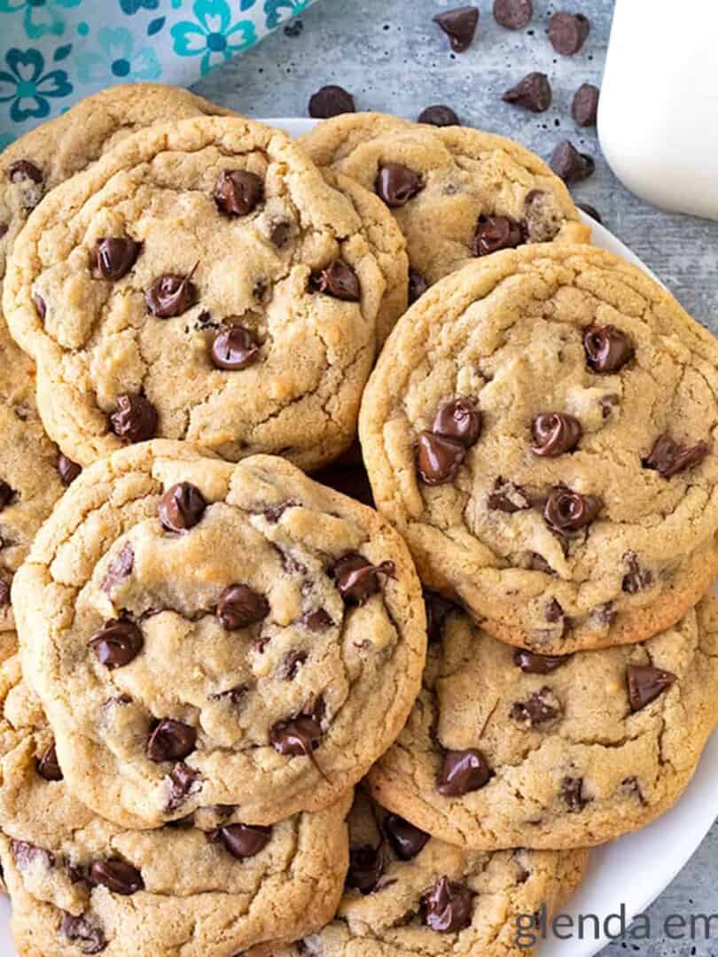 Small Batch Chocolate Chip Cookies on a white plate sitting on a concrete countertop with 3 milk bottles that have steel straws