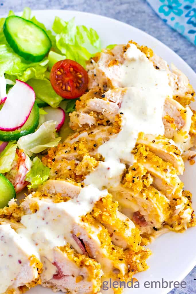 closeup of sliced chicken cordon bleu on a plate with salad