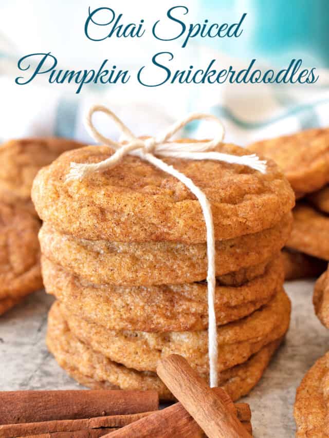 Chai Spiced Pumpkin Snickerdoodles stacked on a counter and tied with a twine bow. Cinnamon sticks and more cookies are strewn about the concretee counter top around the cookie stack