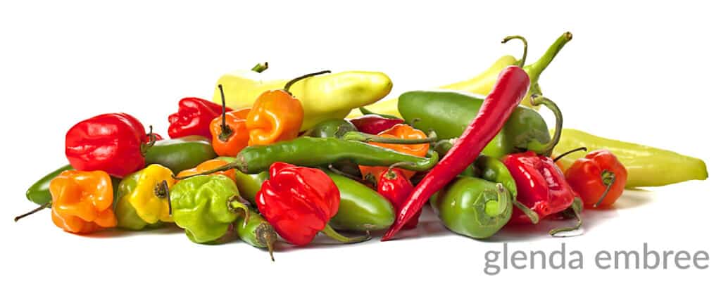 mixture of raw and whole hot chili peppers on a white counter top