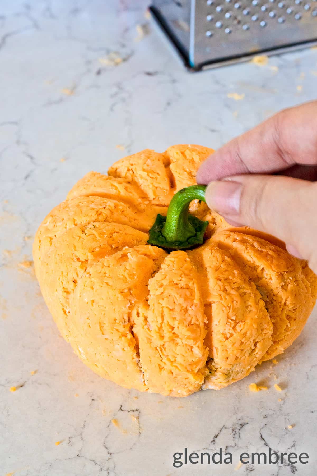 adding bell pepper stem to the top of a cheeseball to make it look like a pumpkin