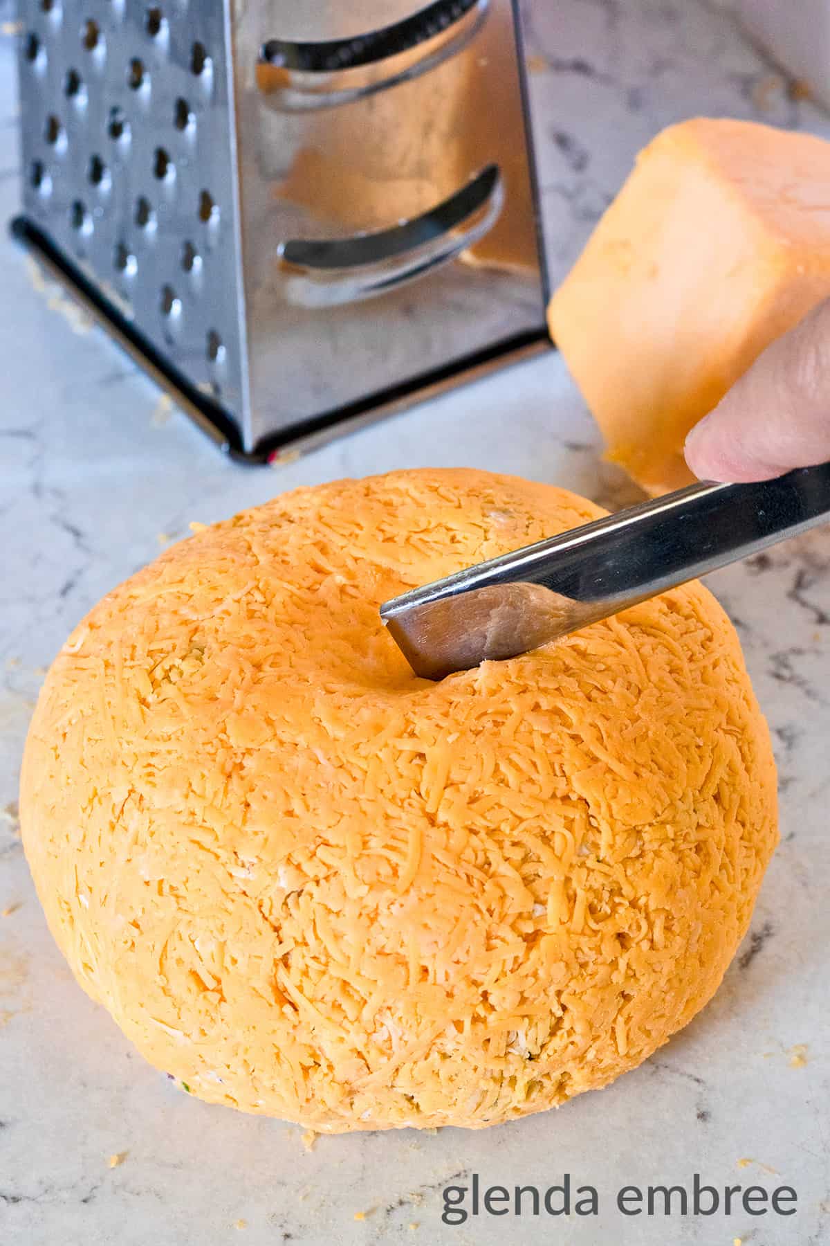 using a butter knife to make decorative indentations into a Bacon and Pineapple Cheese Ball