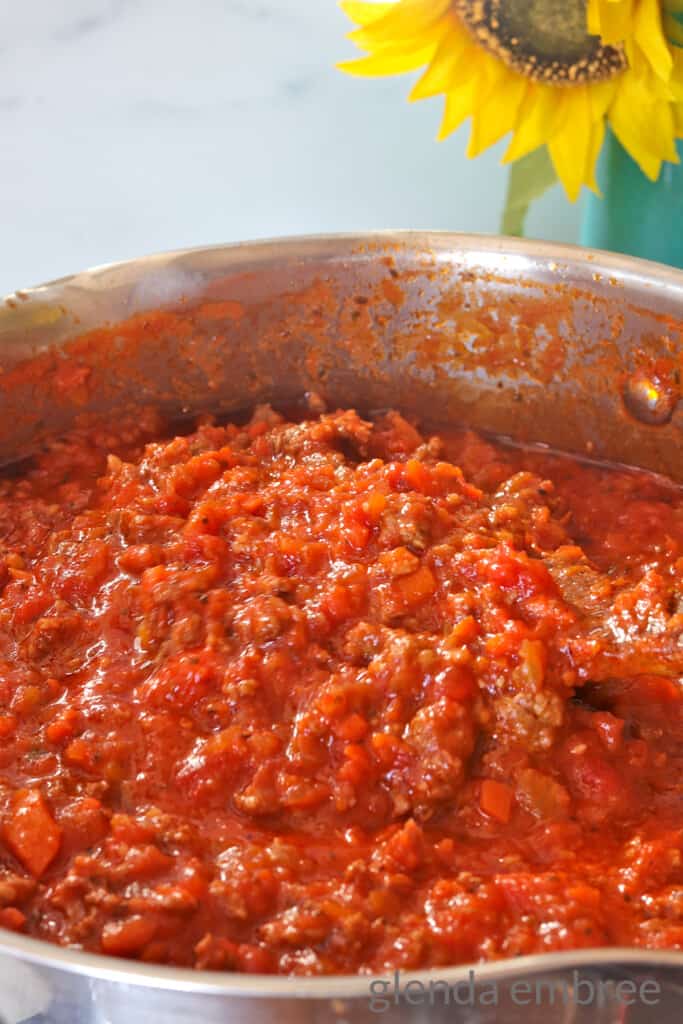 Homemade Bolognese Sause in a Stainless Steel Pot. A spoonful is being lifted out of the pot on a wooden spoon.