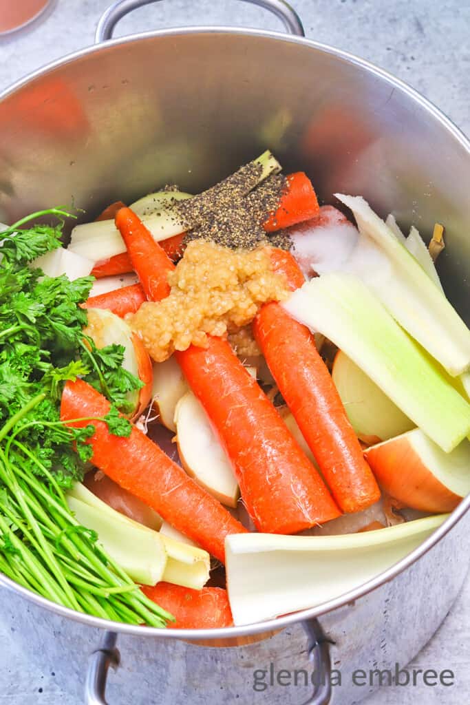 Making Chicken Broth - add carrots, celery, parsley, garlic, salt and pepper to stock pot with chicken pieces and onion