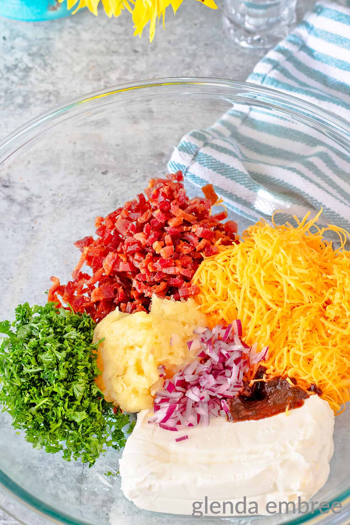 Bacon and Pineapple Cheese Ball Ingredients in a clear glass bowl: cream cheese, crushed pineeapple, bacon, parsely, red onion, Extra Sharp Cheddar and Barbecue Sauce