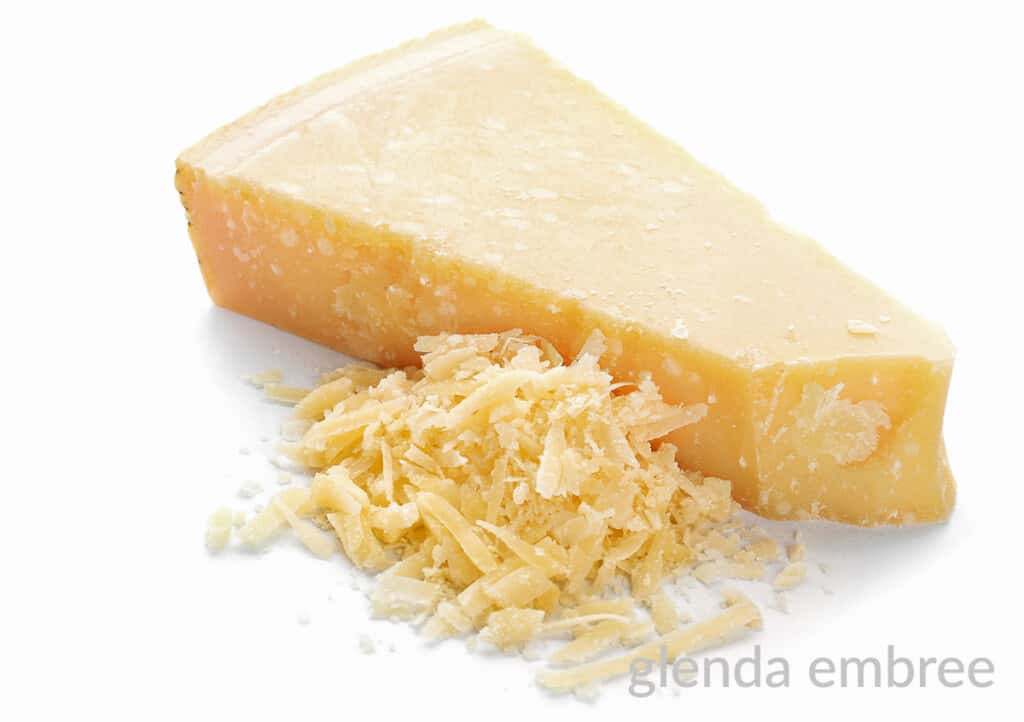 wege of Parmesan cheese with grated Parmesan in a pile beside it