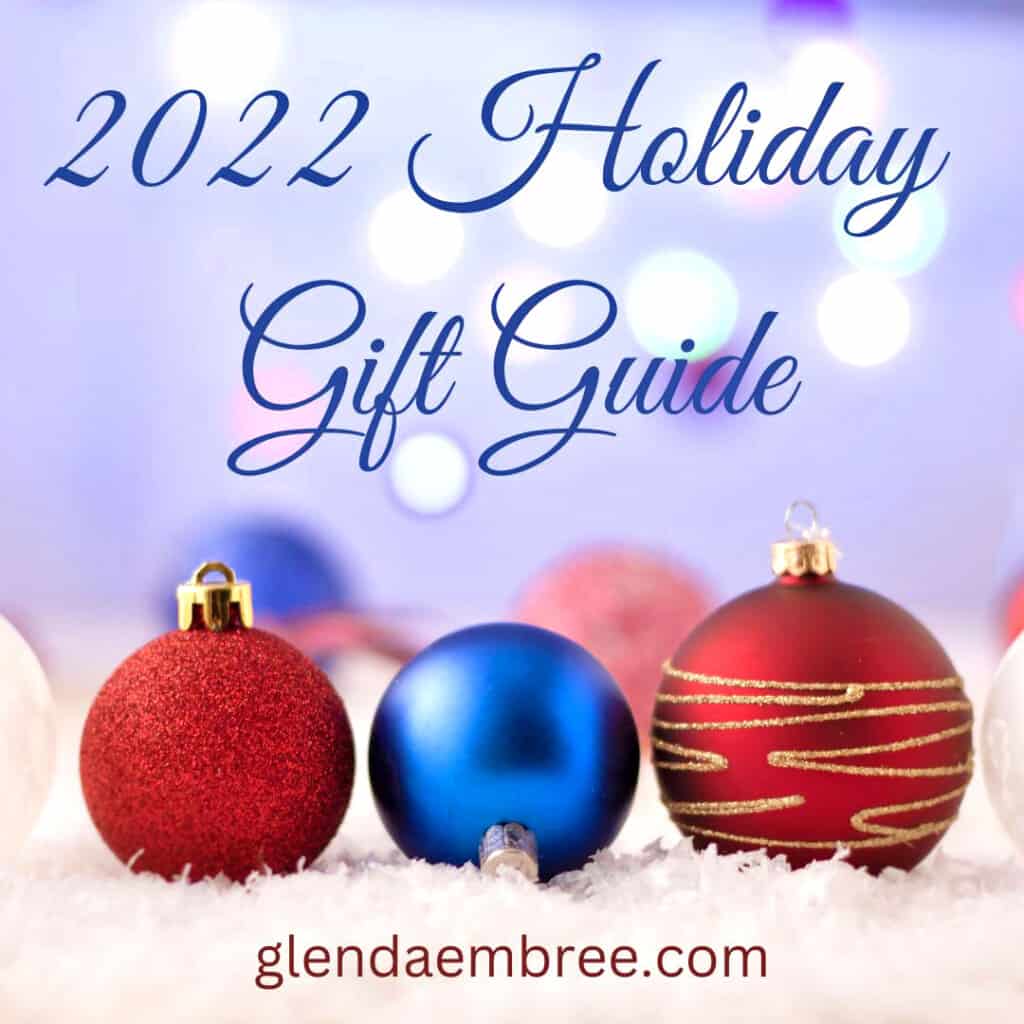 2022 Holiday Gift Guide Image with 1 blue and 2 red Christmas Tree balls on a bed of snow